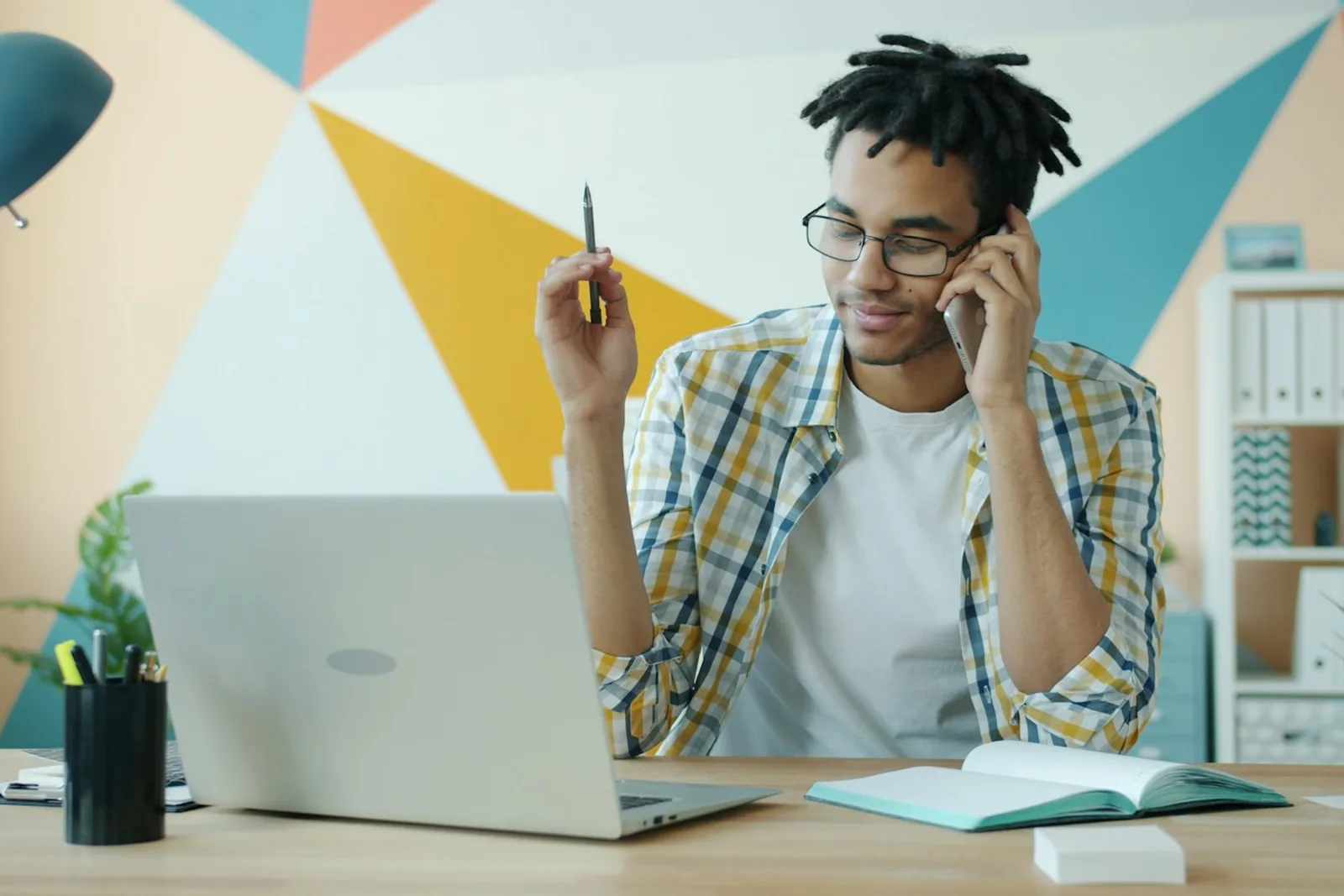 A person taking a call while working on a laptop