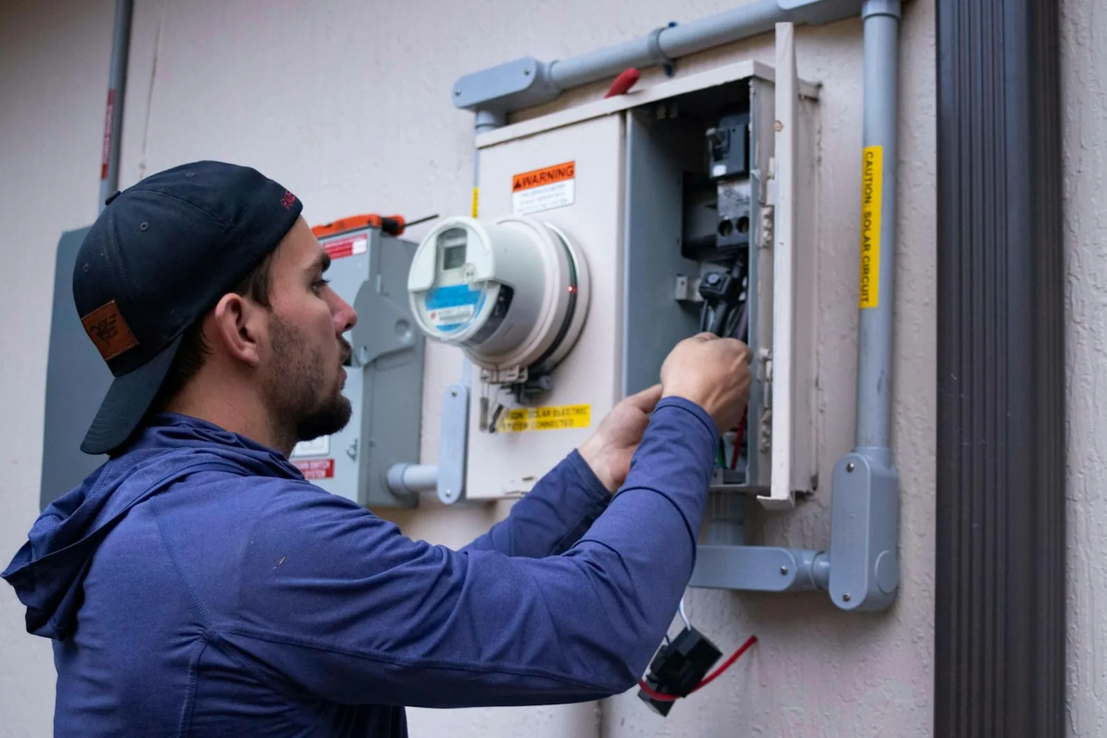 A service technician working on an outdoor utility panel