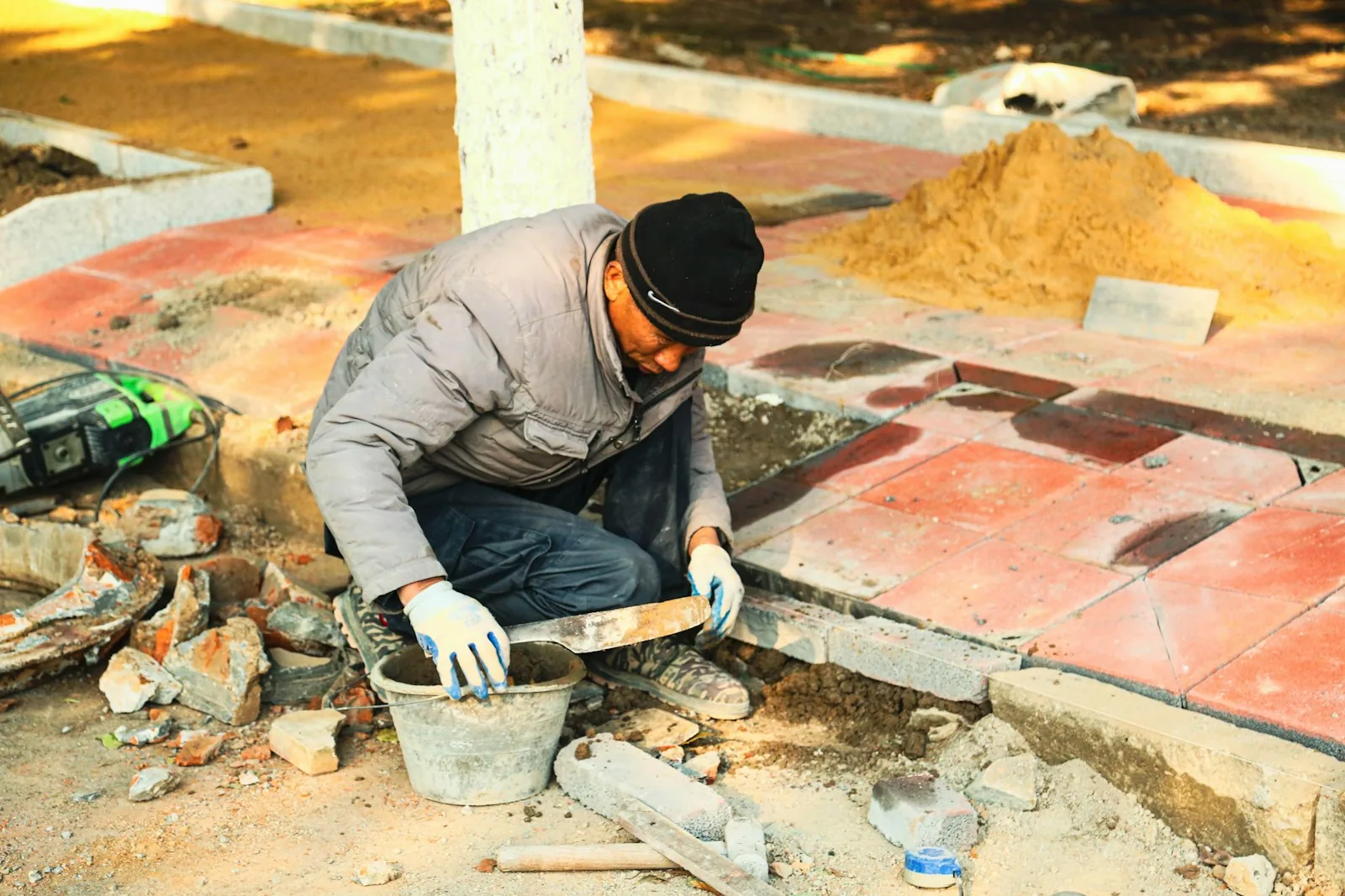 A hardscape installer setting stone on a patio