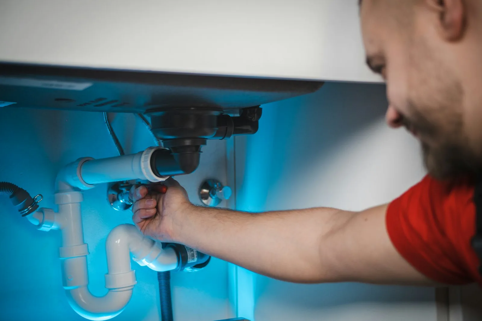 A plumber working on a sink drain line